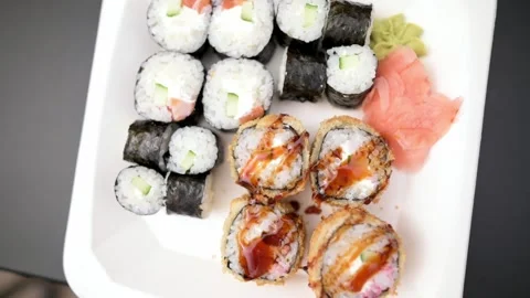 A top-down view of assorted sushi rolls on white plate featuring variety of maki Stock Footage 283424189