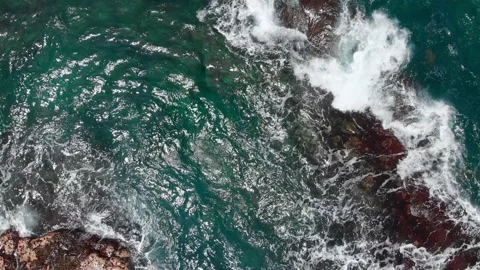 Top-down view of the azure ocean waves foaming and beating against the stone Vídeo Stock 135917424
