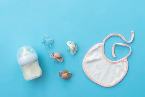 Top-down view of baby essentials with pacifiers on soft blue, offering ample Stock Photos