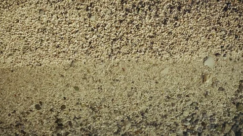 Top-down view of beach sand and small pebbles being washed by a sea wave Stock Footage 313731276