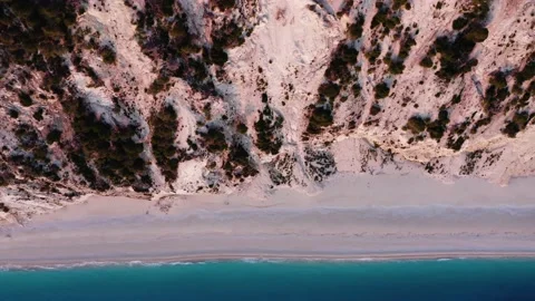 Top down view of beach by tall cliff and turquoise sea. Video stock 158325771