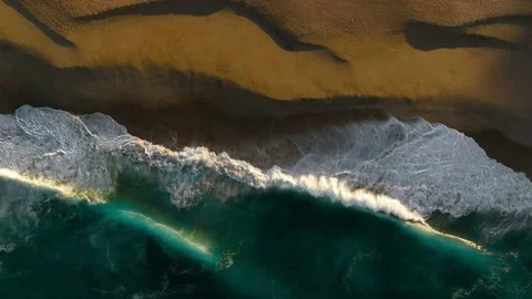 Top down view of beautiful waves crashing at sunrise over sandy beach Stock Footage 236741322