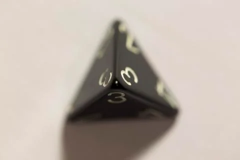Top down view of a black four-sided die showing a three 스톡 사진