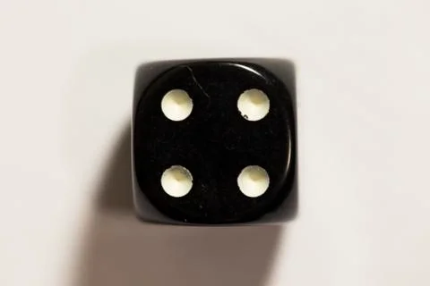 Top down view of a black six-sided die showing a four 스톡 사진