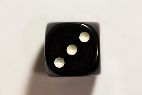 Top down view of a black six-sided die showing a three Photos