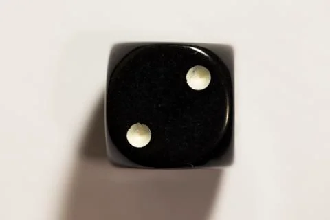 Top down view of a black six-sided die showing a two Photos