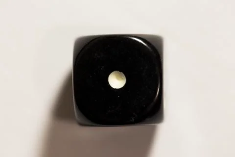 Top down view of a black six-sided die showing a one 스톡 사진