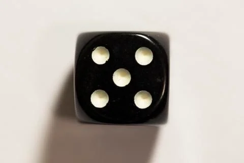 Top down view of a black six-sided die showing a five Photos