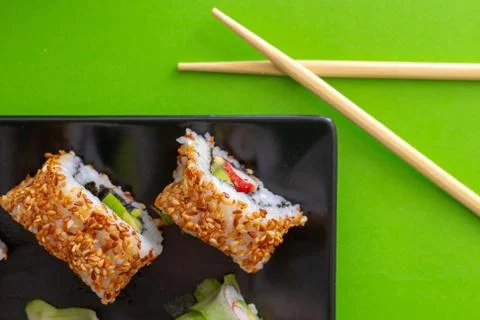 Top down view of a black square plate with multiple sushi rolls with sesame s Stock Photos
