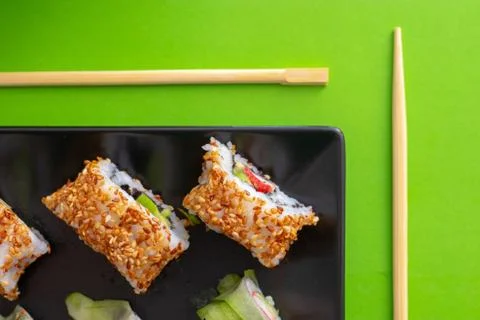 Top down view of a black square plate with multiple sushi rolls with sesame s Stock Photos