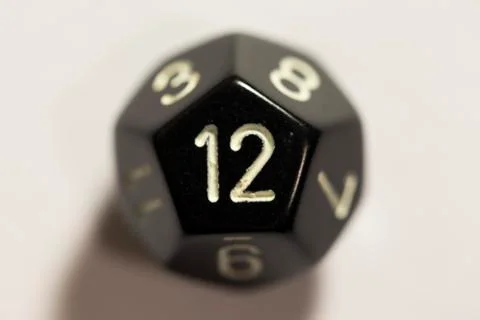 Top-down view of a black twelve sided die, showing a twelve Photos