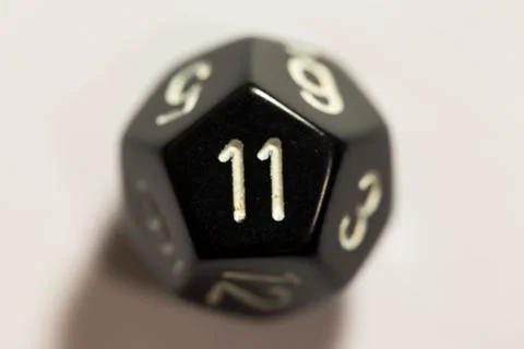 Top-down view of a black twelve sided die, showing an eleven 스톡 사진