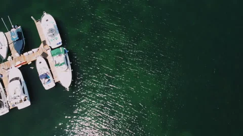 Top down view of boats in harbor, sun reflections spark on the water Video stock 232822592