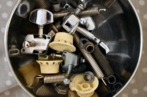 Top-down view of a bowl filled with various electric guitar spare parts and Stock Photos