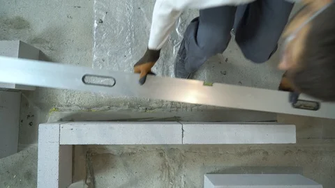 Top down view of builder checking quality of newly built wall with bubble level Stock Footage 104624937