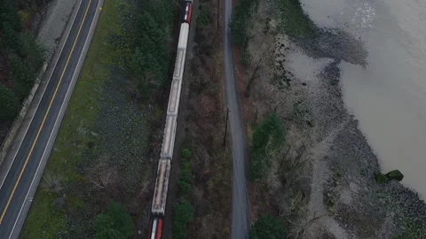 Top down view of cargo train passing by and empty road and river on the sides Stock Footage 138313459
