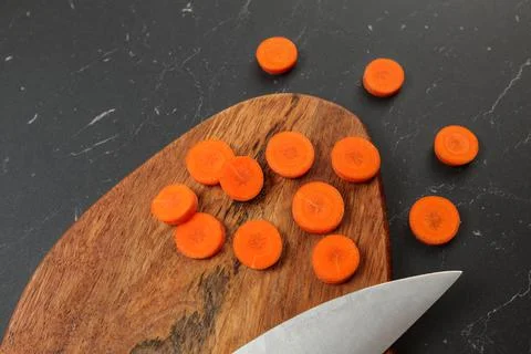 Top down view, carrot sliced to circles, chopping desk, blade of chef knife n Foto stock