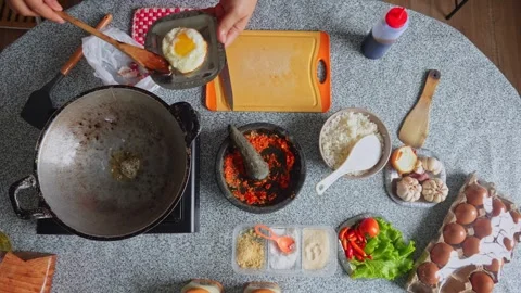 Top-down view of chef frying an egg in hot wok filled with oil, flipping it Stock Footage 342083794