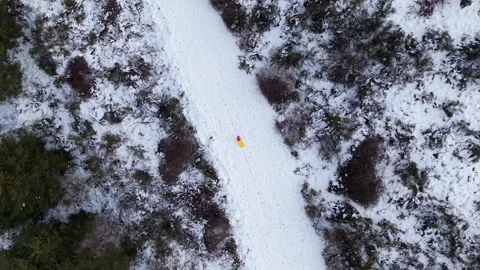 Top-Down View of Child in Winter Clothing Walking with Sled on Snowy Path Stock Footage 327663225