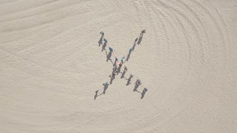 Top down view of children standing in shape of cross and hugging on sand beach Stock Footage 141252903
