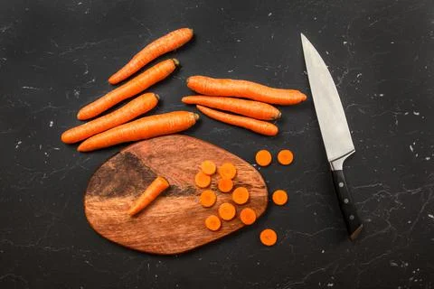 Top down view, chopping board, chef knife and carrot, some of them sliced, on Stock Photos