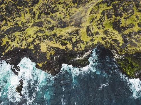 Top down view at a cliff and waves crushing on the rocky volcanic coast on Stock Photos