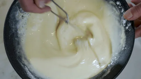 Top down view, close-up, cook mixing and preparing pancake batter in a dark bowl Stock Footage 277452465