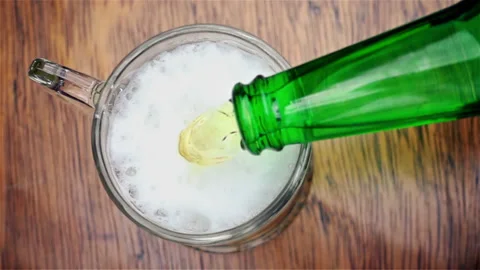 Top Down View of Cold Beer Pouring from Green Bottle into Glass Mug Stock Footage 342970141
