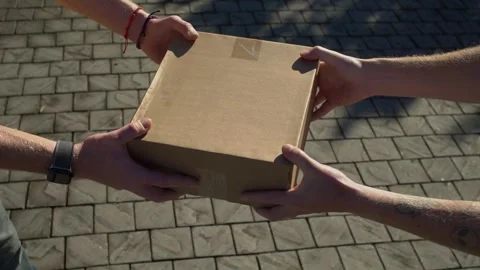 Top down view of courier hands giving cardboard package to customer over brick Stock Footage 336228821