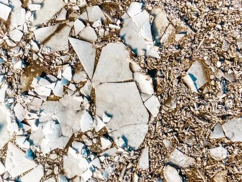 Top Down View of Cracked Ice Sheets with Gravel Fragments Stock Photos