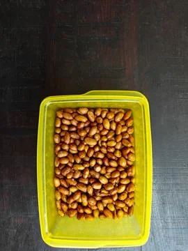 Top down view of crispy fried peanuts inside a yellow plastic container Fotos Stock