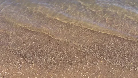 Top down view of crystal clear water with gentle waves softly rolling onto a Stock Footage 330878529