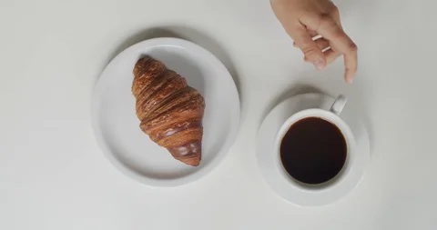 Top down view of cup with coffee and croissant lying on plate indoors  Stock Footage 113729738