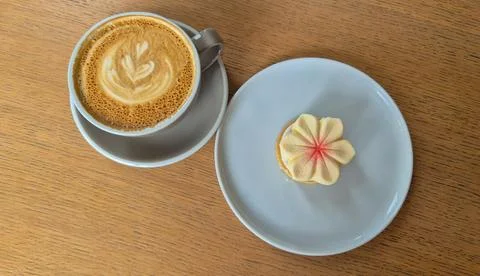 Top-down view of a cup of coffee with latte art served alongside a flower-shaped Stock-Fotos