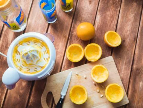 Top down view of cut oranges on a board with juicer on the table Stock Photos