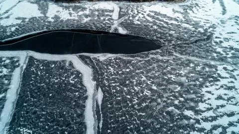Top Down View of Dark Open Water Channel Splitting Frozen Winter Lake Ice Stock Photos