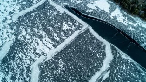 Top Down View of Dark Open Water Channel Splitting Frozen Winter Lake Ice Stock Photos