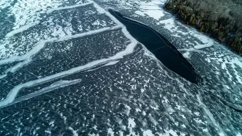 Top Down View of Dark Open Water Channel Splitting Frozen Winter Lake Ice Stock-Fotos