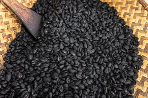 Top down view of dark roasted coffee beans on traditional woven bamboo tray Stock Photos