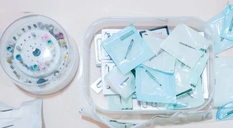 Top down view of dental burs in sterile packages and a rotating organizer tra Stock Photos