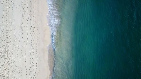 Top down view from drone of blue calm ocean and beach with footprints Stock Footage 118937765