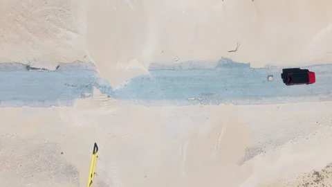 Top-Down View of Drone Moving with Red Car Driving Out of Frame on Beach Road, S Stock Footage 306330284