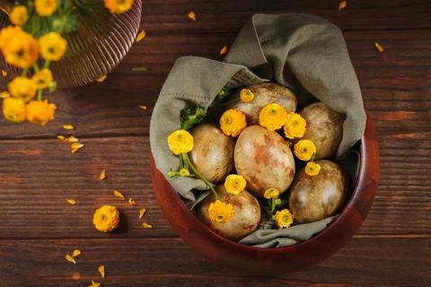 Top-down view of Easter eggs and yellow flowers in a wooden bowl Stock Photos