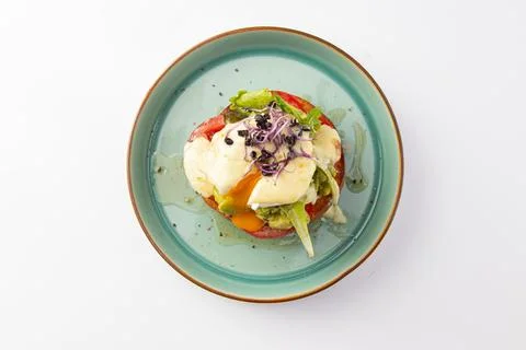 Top down view of eggs Benedict on tomato with avocado Stock Photos