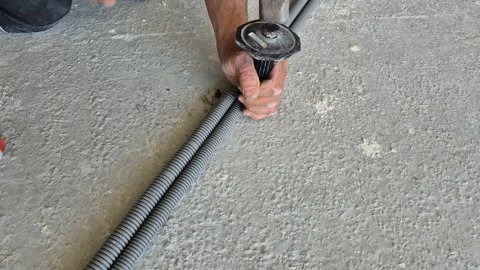 Top-down view of electrician hammering a nail-in anchor for conduit clamp Stock Footage 345665725