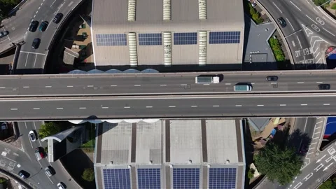 Top down view of an elevated urban motorway cutting between industrial roofs Stock Footage 343473124