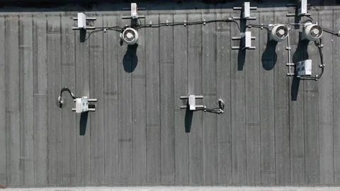 Top-down view of flat rooftop lighting equipment on a dark industrial roof Stock Footage 341712998