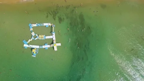 Top down view fly over tourist and inflatable floating playground on the beach. Stock Footage 130668860