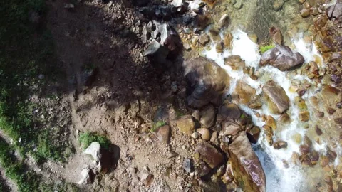 Top down view flying over rushing mountain river and giant wet boulders Stock Footage 335093630