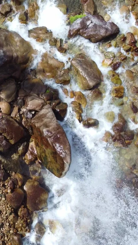Top down view flying over rushing mountain river and giant wet boulders Stock Footage 336691692